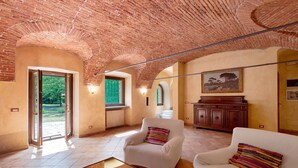 A spacious room with a high brick ceiling, a large window, and a view of greenery outside. - Cascine di Villa Schella with Pool – Relaxing Oasis for Groups and Families (Ovada)