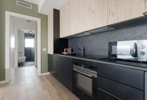 A modern kitchen with dark cabinetry, a built-in oven, and a microwave. - GuestHost - Modern and welcoming 50 square meters apartment, perfect for four people, located on the eighth floor of a building with an elevator (NOT accessible to disabled guests).The property is located in the Cascina Merlata neighborhood, a growing ar (Milan)