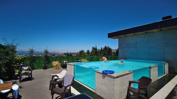 An outdoor swimming pool with a view of the city, surrounded by deck chairs and a wooden deck. - AHSA VILLA WONDERFOUL SEA VIEW AND SWIMMING POOL (İstanbul)