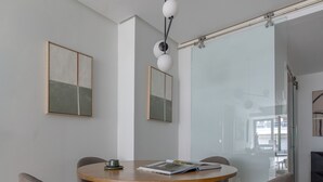Een moderne eetruimte met een ronde houten tafel, vier grijze stoelen en een centraal hanglamp.