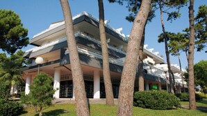 Un edificio de varios pisos con un diseño arquitectónico moderno, que presenta un techo plano y grandes ventanales.