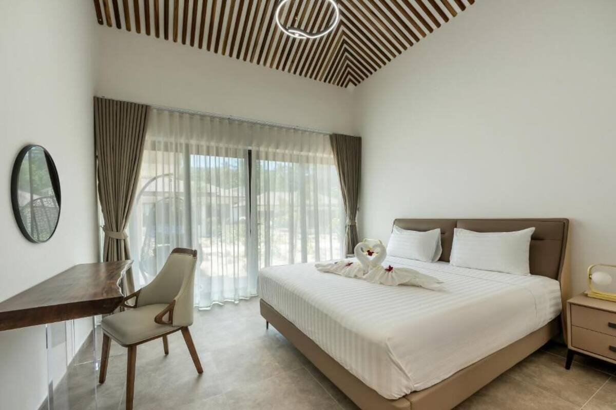 A hotel room with a bed, a desk, a chair, and a nightstand.