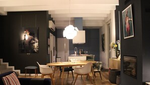 Un soggiorno moderno con un divano scuro, un tavolo da pranzo in legno con sedie e un angolo cottura sullo sfondo.