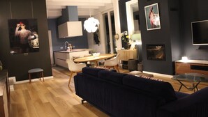 Un soggiorno moderno con un divano blu scuro, un tavolino in vetro e un'area pranzo con un tavolo e sedie in legno.
