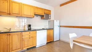 A kitchen with wooden cabinets, a microwave, a refrigerator, a dishwasher, and a dining table with chairs. - Large Family Apartment - Mountain View - Sleeps 7/8 (Saint-Sorlin-d´Arves)