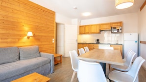 A cozy living area with a sofa, a dining table with chairs, wooden cabinets, a microwave, and a refrigerator. - Large Family Apartment - Mountain View - Sleeps 7/8 (Saint-Sorlin-d´Arves)