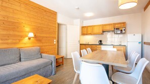 Un área de estar acogedora con un sofá, una mesa de comedor con sillas, armarios de madera, un microondas y un refrigerador.