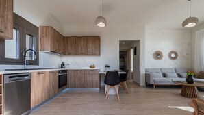 Una cuina moderna amb armaris de fusta, un rentaplats i una zona de menjador amb taula i cadires.