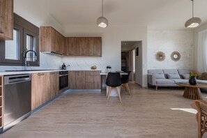 Eine moderne Küche mit Holzausstattung, einem Geschirrspüler und einem Essbereich mit Tisch und Stühlen.