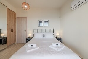 Un dormitorio ordenado con una cama grande, dos mesitas de noche con lámparas, un armario de madera y un aplique de techo.