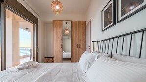 Habitación de hotel con una cama grande, un armario de madera, un taburete pequeño y un balcón con vistas.