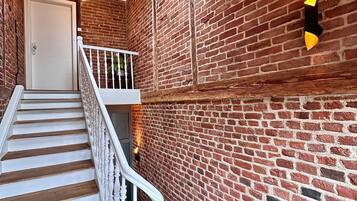 Un escalier avec des balustrades blanches et des marches en bois menant à une porte surmontée d’une lucarne.