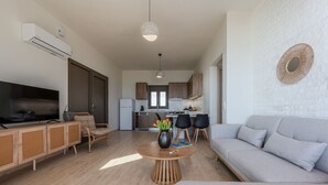 Una sala de estar moderna con sofá, televisión y comedor.
