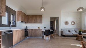 Una cocina moderna con armarios de madera, lavavajillas y un comedor con mesa y sillas.