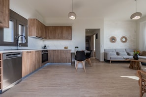 Une cuisine moderne avec des meubles en bois, un lave-vaisselle et un coin repas comprenant une table et des chaises.