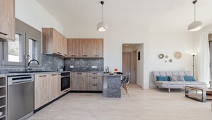 A modern kitchen with wooden cabinets, a built-in oven, and a central island. - Kedros Villa Exi (Viannos)