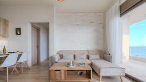 A modern living room with a sofa, a coffee table, and a dining area with chairs. - Kedros Villa Tessera (Viannos)