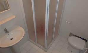Ein Badezimmer mit weißem Waschbecken, Toilette und einer Duschkabine.
