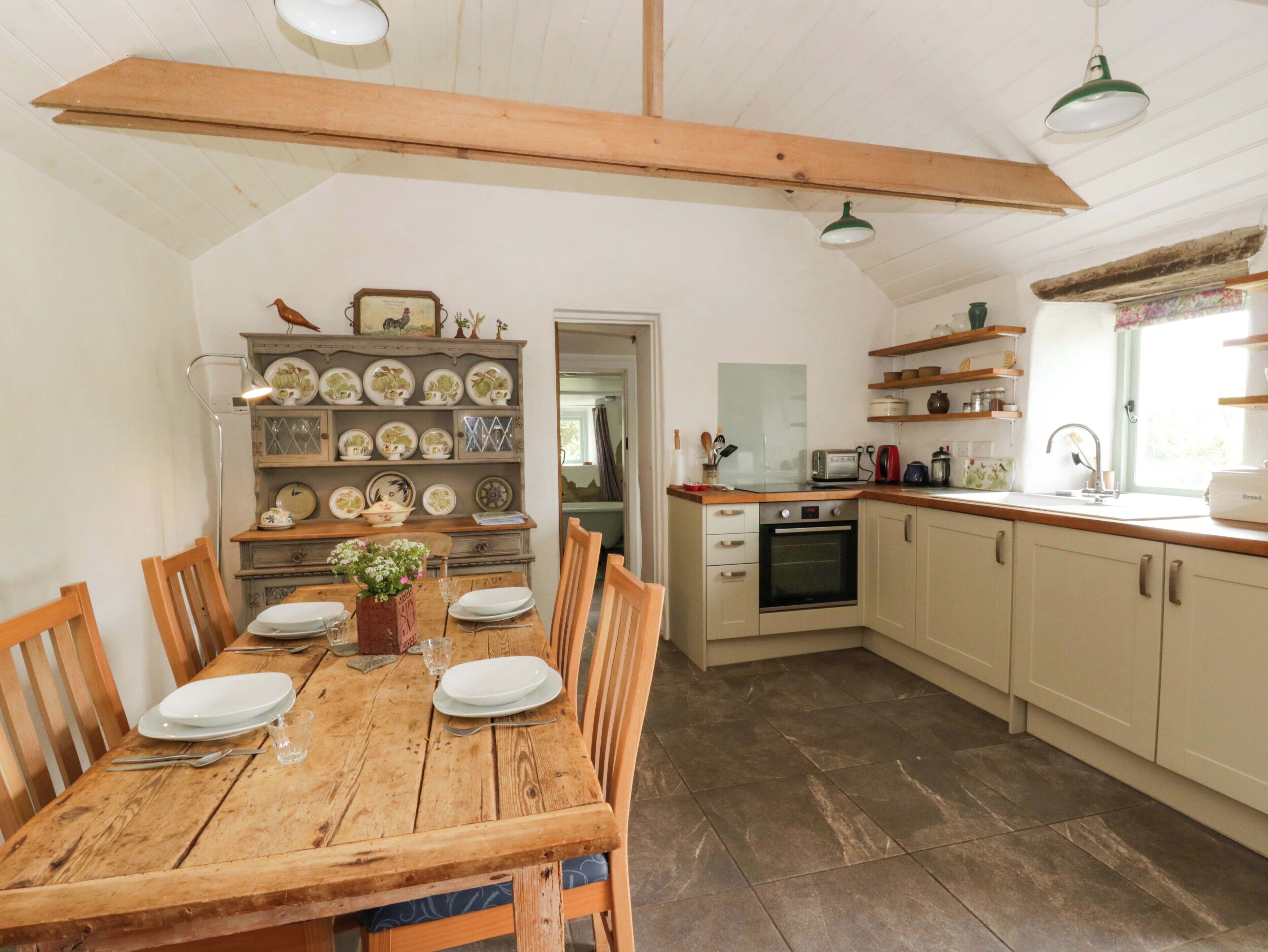 Een keuken met een houten tafel, kasten en diverse keukenapparaten.