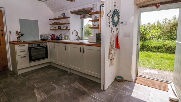 A kitchen with a built-in oven, a sink, and a window. - Rhos Y Clegyrn (Goodwick)