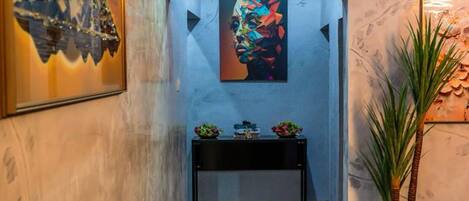 A hallway with a black tiled floor, a blue sofa, and artwork on the walls.