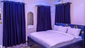 Une chambre à coucher avec un lit, des rideaux foncés, un miroir et un appareil de climatisation.