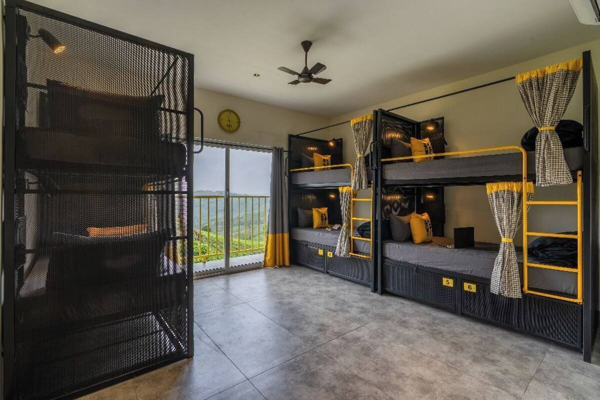 Une chambre de dortoir avec des lits superposés, un balcon et une porte-moustiquaire.
