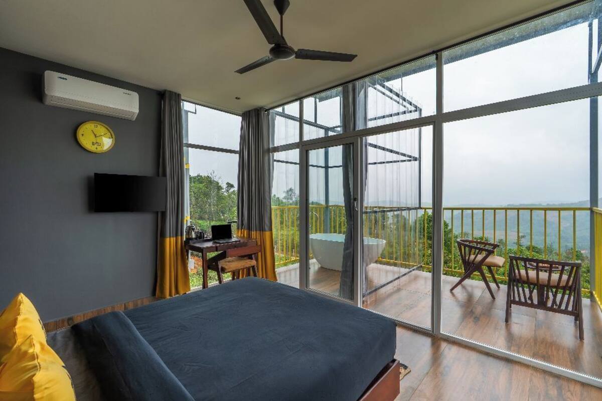 Une chambre à coucher comprenant un lit, un bureau, une chaise, une télévision et un balcon avec vue.