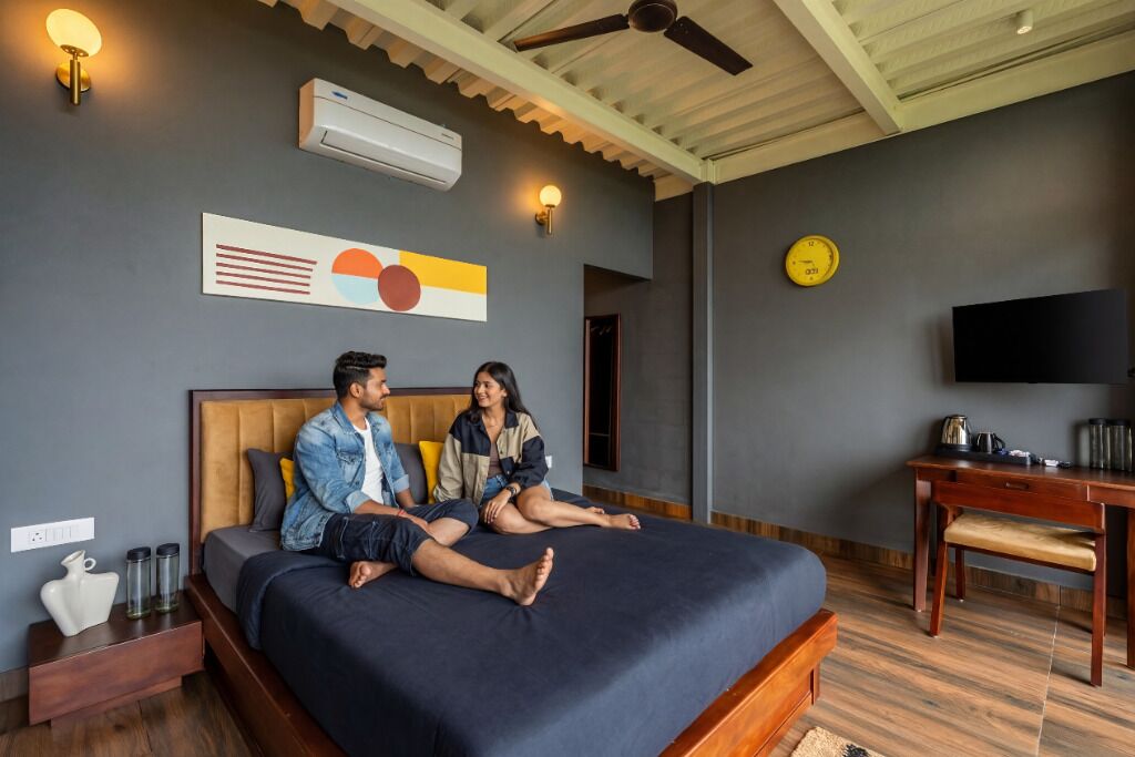 Habitación de hotel moderna con una cama grande, un escritorio, un televisor y un reloj de pared.