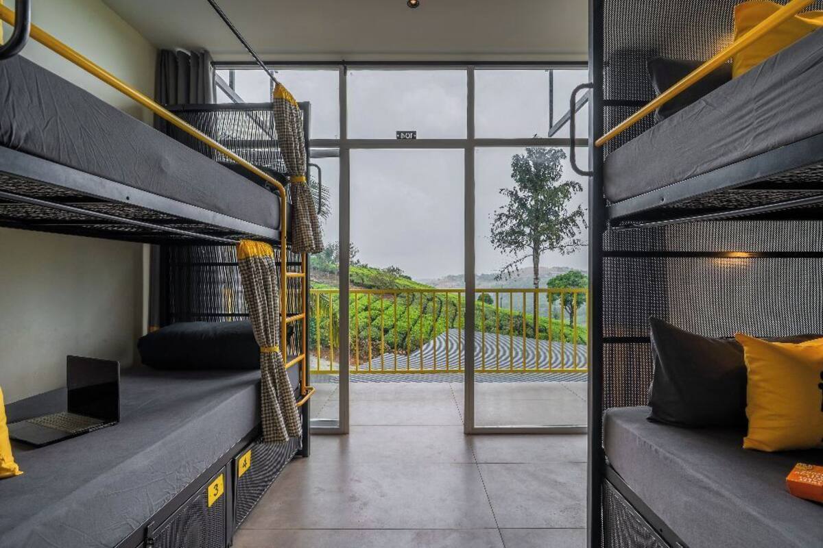 Une chambre avec des lits superposés offrant une vue sur un paysage verdoyant grâce à de grandes fenêtres.