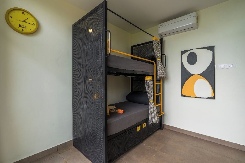 A bunk bed with a ladder, a clock, and an abstract painting on the wall.