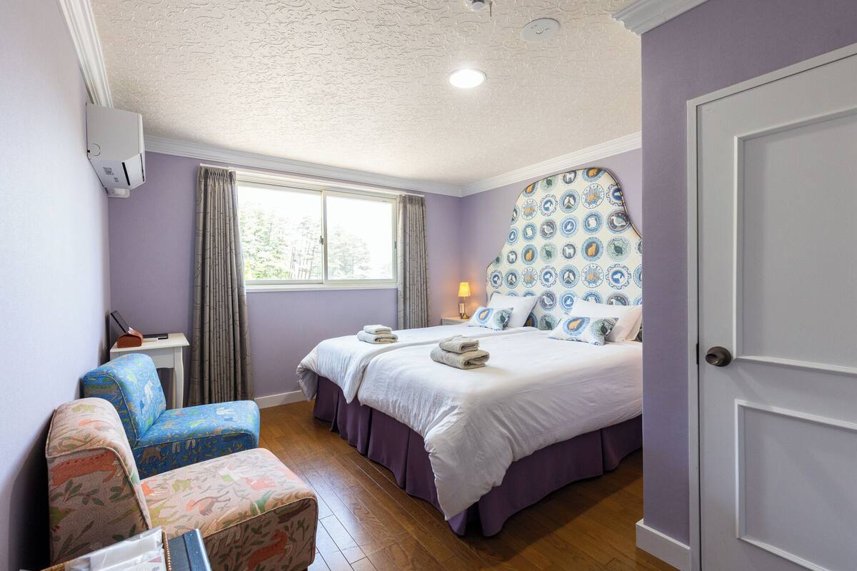 Un dormitorio con dos camas, una ventana, un escritorio y una silla.