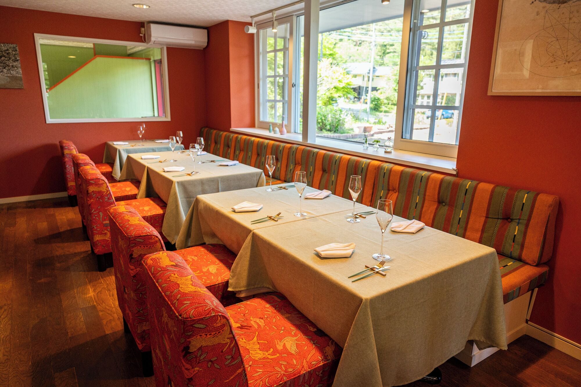 Un comedor con mesas dispuestas para cuatro, bancos y ventanas amplias.