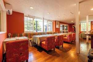 Un restaurante con suelos de madera, mesas con manteles blancos y sillas rojas con estampado.