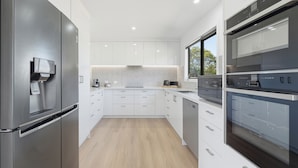Una cocina moderna con electrodomésticos de acero inoxidable, armarios blancos y suelo de madera.