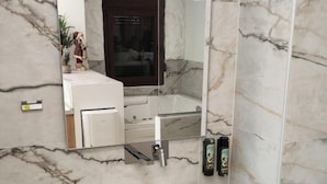 A modern bathroom with a marble backsplash, a large mirror, a white sink, and a wooden floor. - Lūma Retreat (Kastoria)