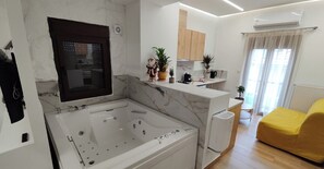 Ein modernes Wohnzimmer mit einer großen weißen Badewanne, einem gelben Sofa und einer Küchenzeile mit Holzschränken und Topfpflanzen.