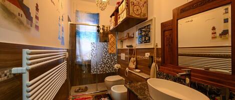 A modern bathroom with a large mirror, a freestanding toilet, and a vanity with a sink.