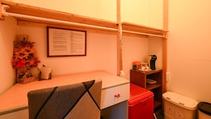 A compact room with a bed, a small desk, a red refrigerator, a trash bin, and a framed menu on the wall. - La Tana di Misha - Genova (Genova)