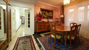 A dining area with a wooden table and chairs, a patterned rug, and a painting on the wall. - La Tana di Misha - Genova (Genova)