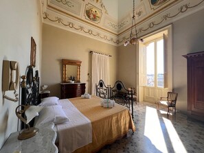 Une chambre d’hôtel avec un grand lit, un bureau, une chaise, une armoire et une vue sur la ville par la fenêtre.