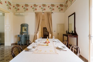 Une salle à manger avec une table dressée pour six personnes, un miroir et un décor floral au plafond.