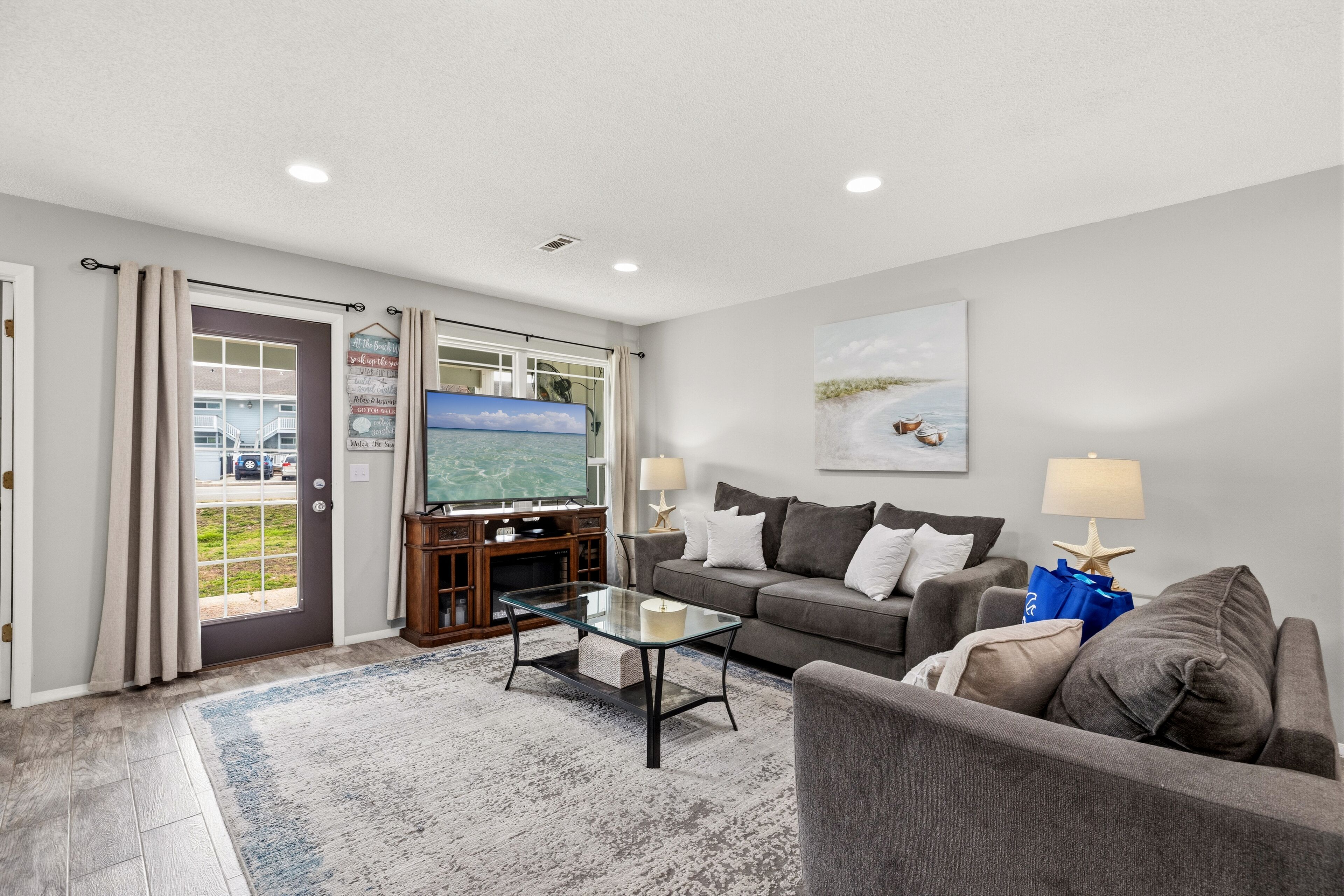 A living room with a grey sofa, a glass coffee table, and a television.