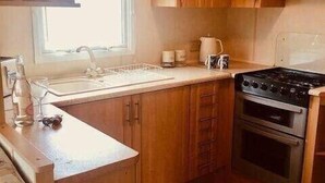 Una cocina funcional con armarios de madera, un lavamanos, una estufa y un ventanal.