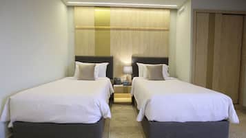 A hotel room with two beds, a nightstand, a lamp, and a wooden panel wall.