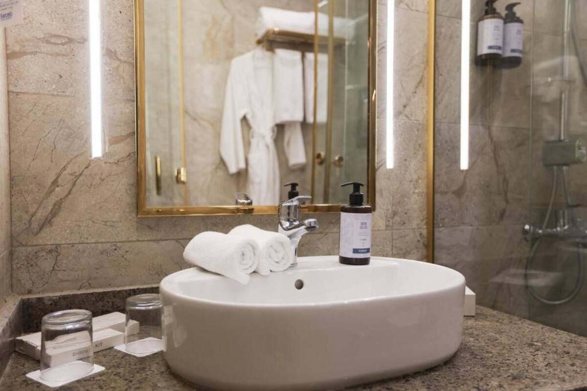 Un baño con lavamanos de mármol, un espejo y una cabina de ducha de vidrio.
