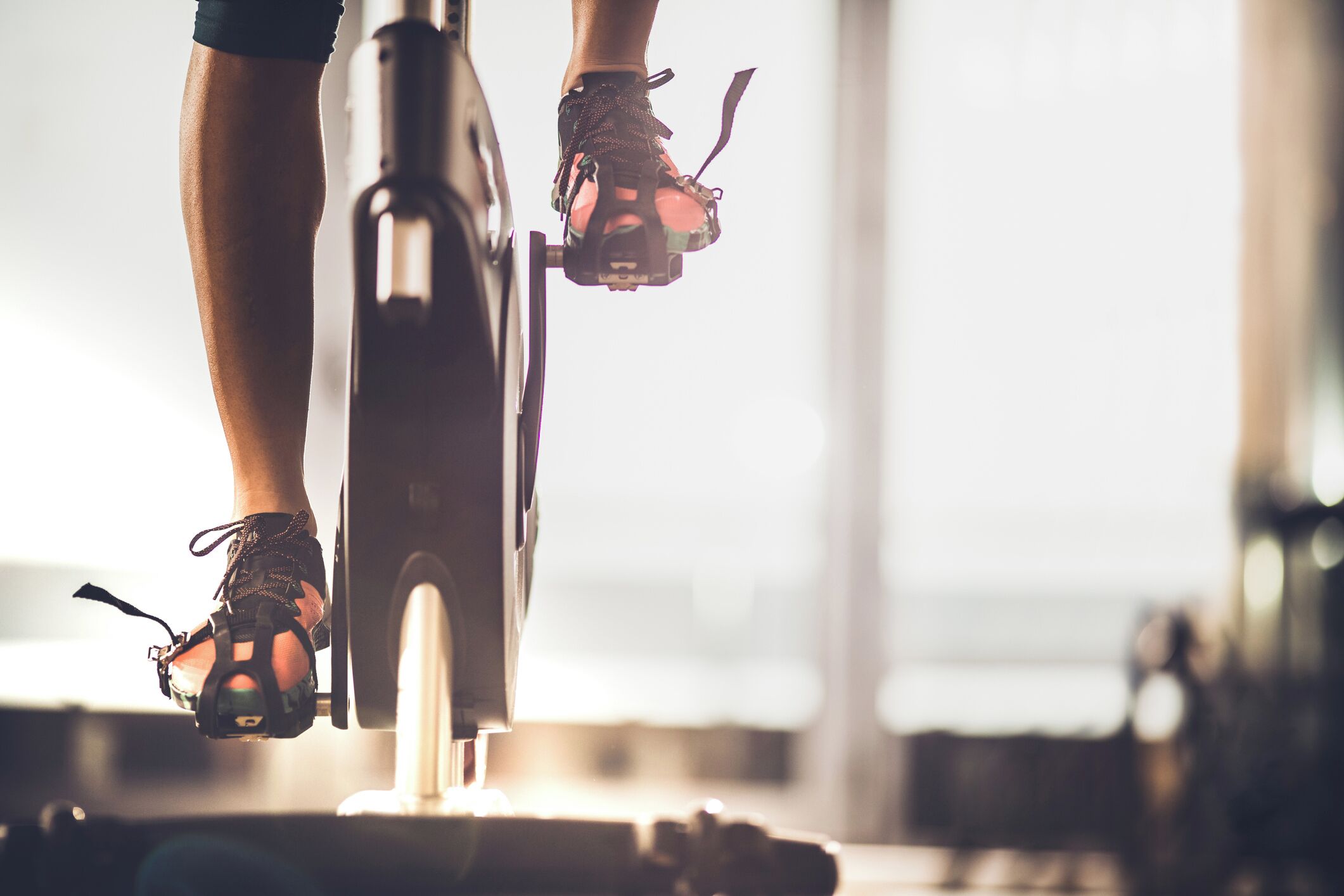 A stationary bike with a person pedaling, wearing cycling shoes.