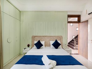 Une chambre d’hôtel avec un lit, une table de chevet, une petite table sur laquelle se trouve un vase, et un escalier menant à un autre espace.