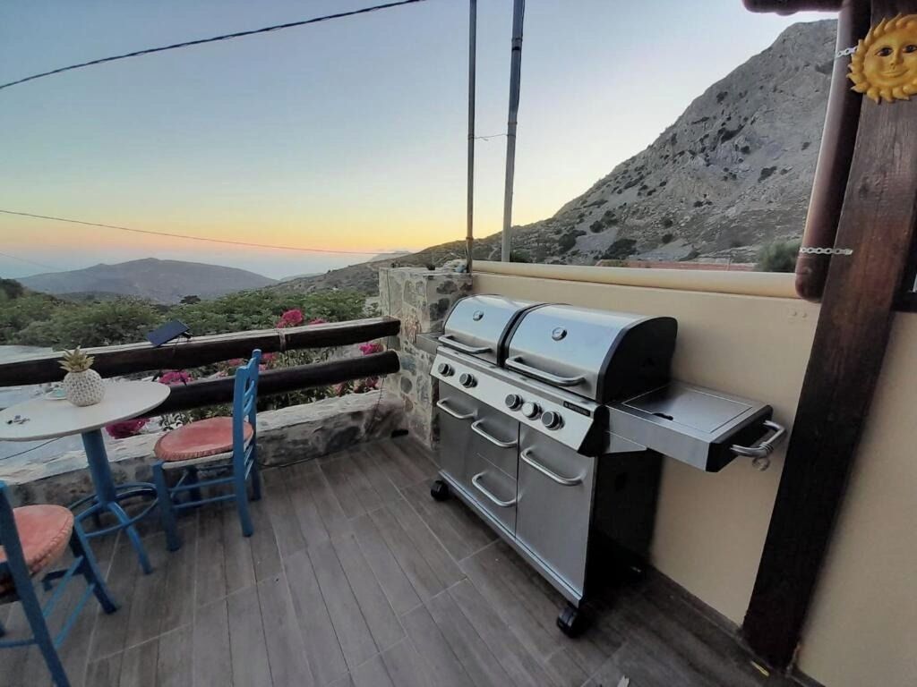 Un patio con una parrilla de acero inoxidable, una mesa con sillas y vistas a las montañas.