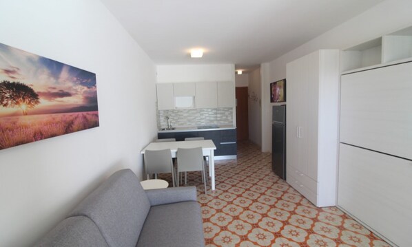 Un espacio habitable compacto con kitchenette, comedor y sofá.